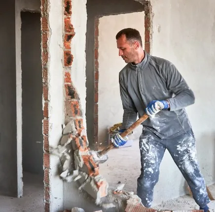 Albañil comprobando si una pared es muro de carga antes de derribarla en Granada